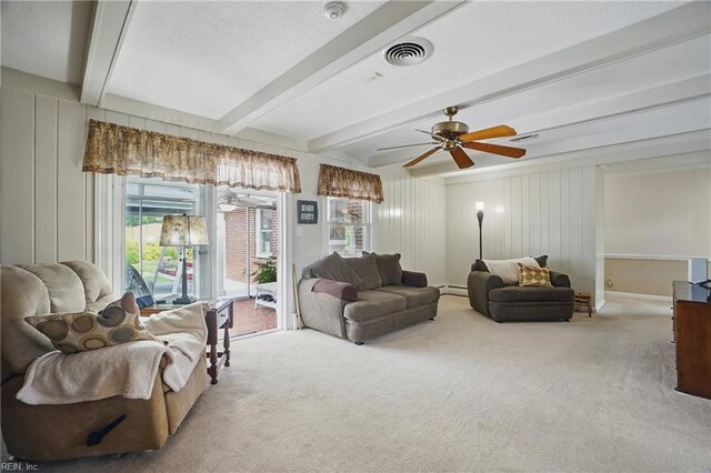 carpeted living area with a healthy amount of sunlight, a baseboard heating unit, beam ceiling, and visible vents