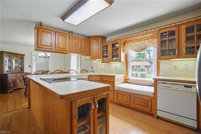 kitchen featuring light wood-style flooring, brown cabinets, black electric stovetop, and dishwasher