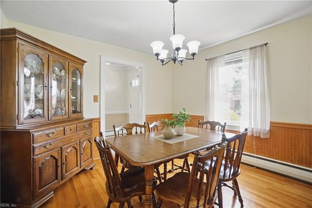 dining area with light wood-style floors, wainscoting, a baseboard heating unit, and a notable chandelier