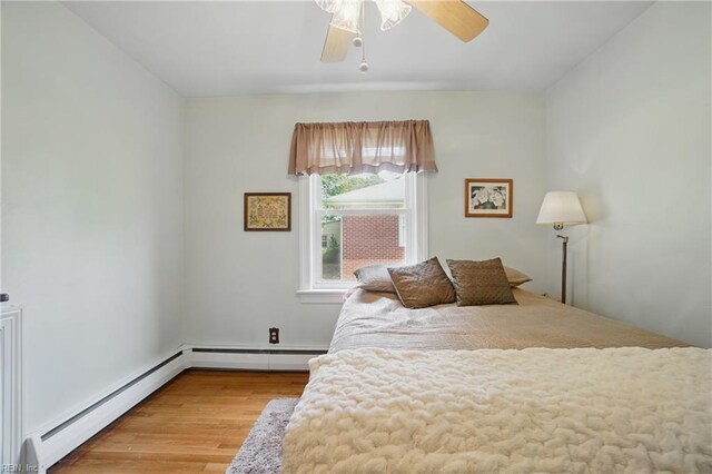 bedroom featuring baseboard heating, a ceiling fan, and wood finished floors