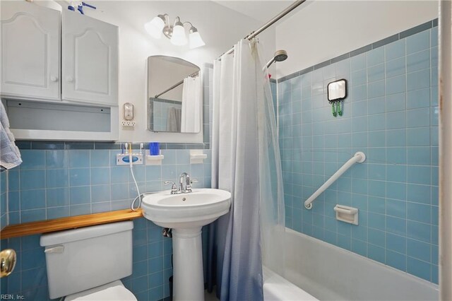 full bathroom with toilet, tile walls, shower / bath combination with curtain, and a sink