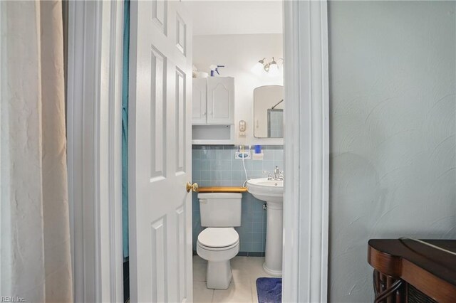 bathroom featuring tile walls, tile patterned floors, and toilet