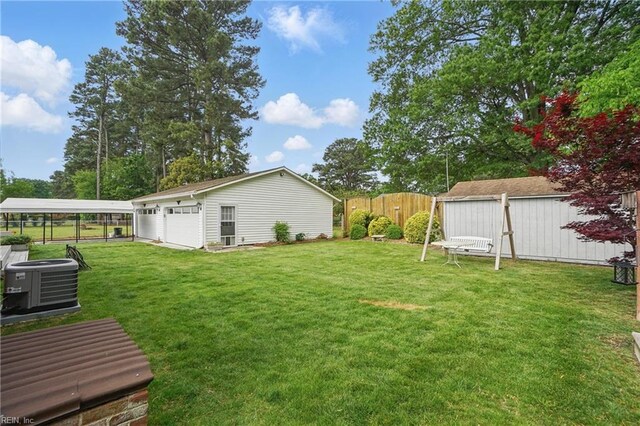 view of yard with central air condition unit, fence, an outbuilding, and a detached garage