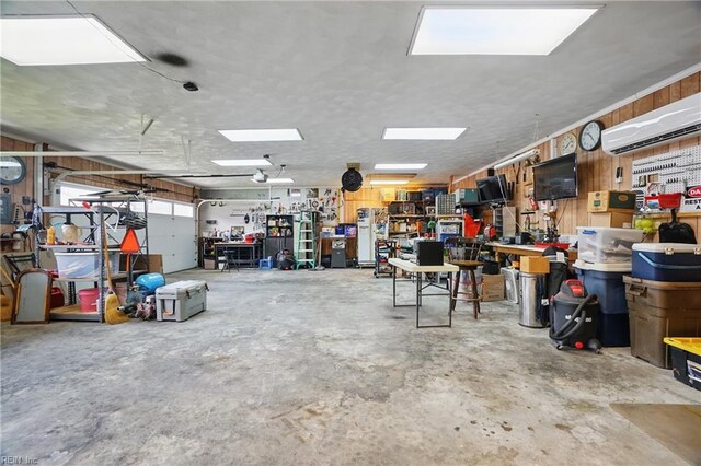 garage featuring wooden walls, a workshop area, and a wall mounted air conditioner