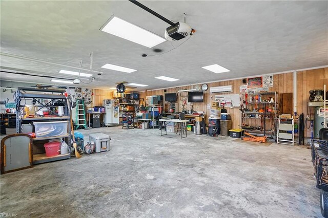 garage with a garage door opener, a wall mounted AC, wooden walls, and a workshop area