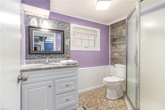bathroom featuring crown molding, a stall shower, vanity, a wainscoted wall, and toilet