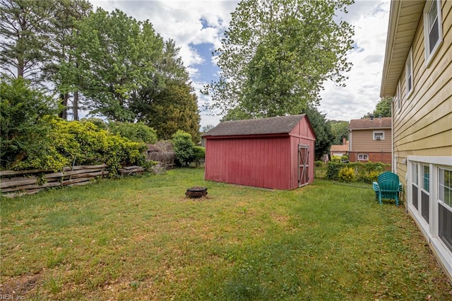 view of yard featuring a storage shed, an outdoor structure, a fenced backyard, and a fire pit