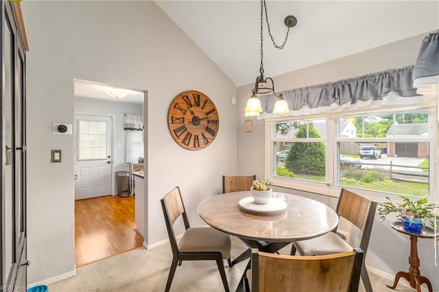 dining room featuring light colored carpet, baseboards, vaulted ceiling, and plenty of natural light
