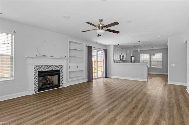 159 Stoney Ridge Ave, Suffolk, VA 23435 - unfurnished living room with ceiling fan, a tiled fireplace, built in features, wood finished floors, and baseboards