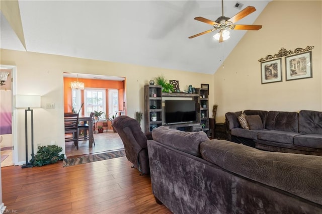 living room with visible vents, ceiling fan with notable chandelier, wood finished floors, and vaulted ceiling