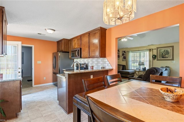 kitchen with visible vents, baseboards, a textured ceiling, stainless steel microwave, and backsplash