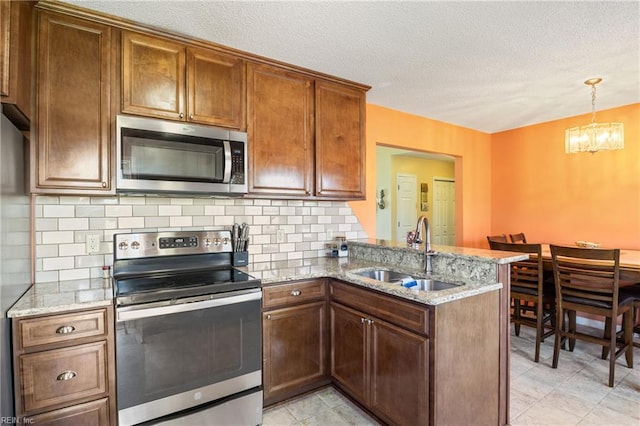 kitchen featuring appliances with stainless steel finishes, a sink, a chandelier, a peninsula, and tasteful backsplash