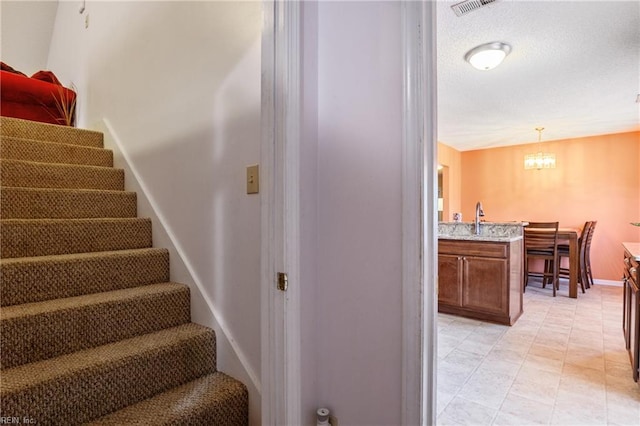 staircase with baseboards, a chandelier, and visible vents