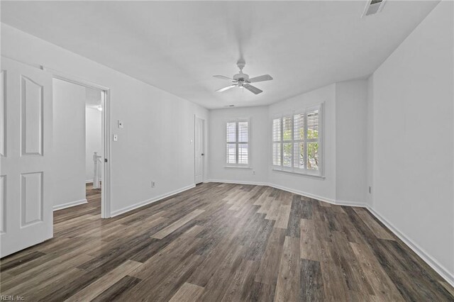 interior space featuring dark wood-style flooring, a ceiling fan, visible vents, and baseboards