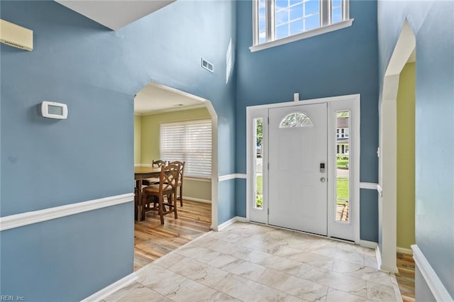 foyer with arched walkways, baseboards, and a wealth of natural light