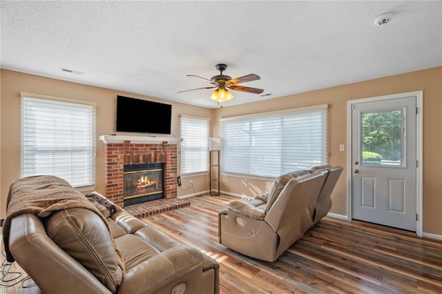 living area with visible vents, a ceiling fan, a textured ceiling, and wood finished floors