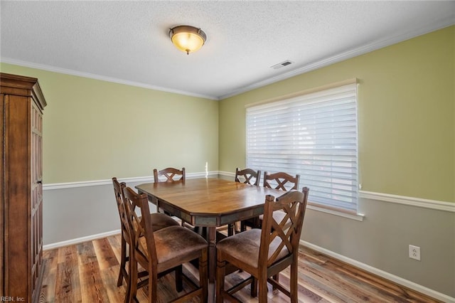 dining room with a textured ceiling, wood finished floors, and visible vents