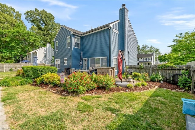 rear view of house featuring fence, a patio, a chimney, and a yard