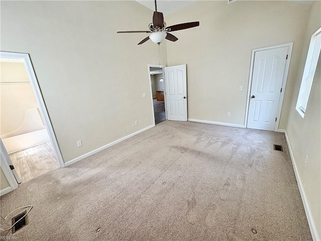 unfurnished bedroom with carpet floors, baseboards, high vaulted ceiling, and visible vents