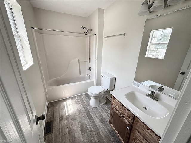 bathroom with vanity, shower / bathtub combination, toilet, wood finished floors, and visible vents