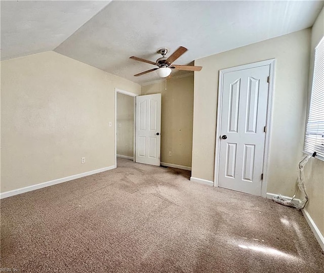 unfurnished bedroom featuring vaulted ceiling, baseboards, ceiling fan, and carpet flooring