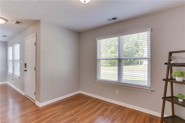 unfurnished room featuring baseboards, a healthy amount of sunlight, and wood finished floors