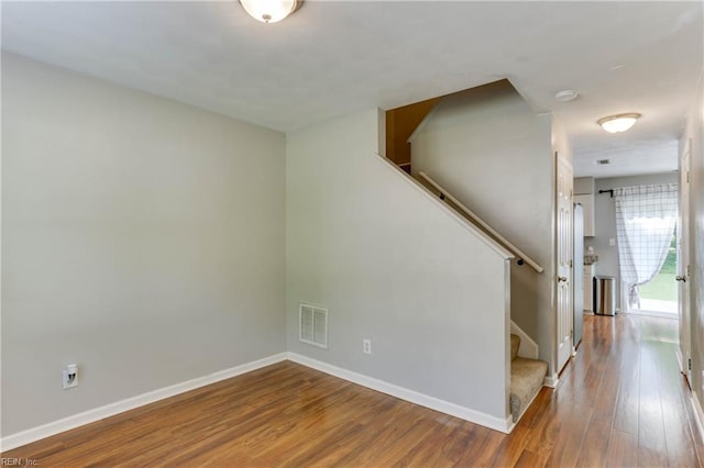 spare room with visible vents, baseboards, wood finished floors, and stairway