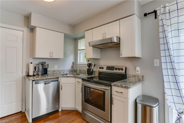 kitchen with a sink, white cabinetry, appliances with stainless steel finishes, and under cabinet range hood