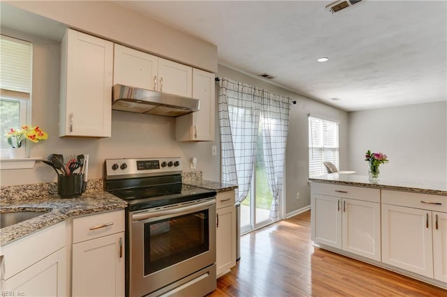 kitchen featuring under cabinet range hood, visible vents, light wood-style flooring, and electric stove