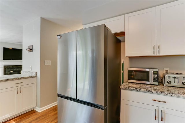 kitchen with stainless steel appliances, light stone countertops, light wood-style flooring, and a toaster