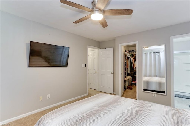 bedroom with light colored carpet, baseboards, a closet, connected bathroom, and a spacious closet