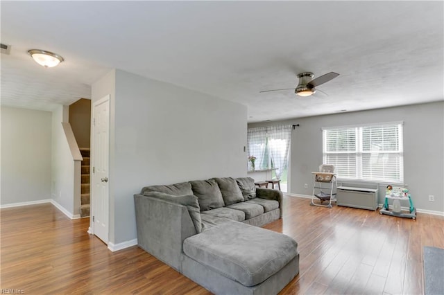 living room featuring baseboards, stairs, ceiling fan, and wood finished floors