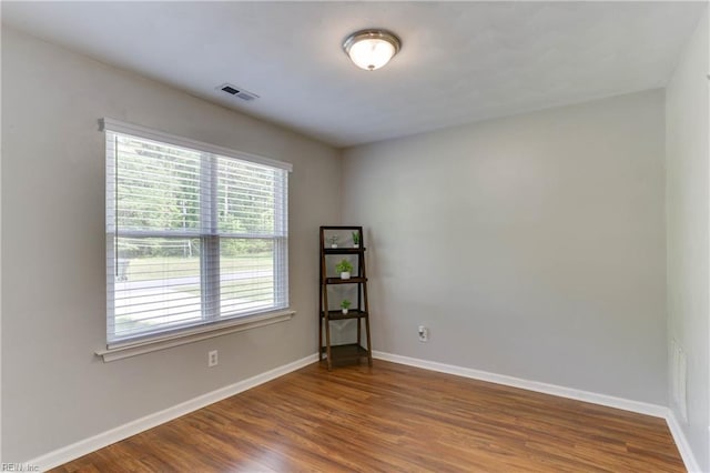 empty room with visible vents, baseboards, and wood finished floors