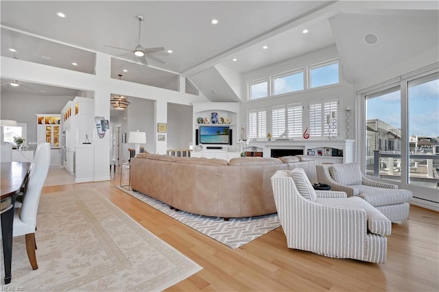 living room with high vaulted ceiling, ceiling fan, a fireplace, and light wood finished floors