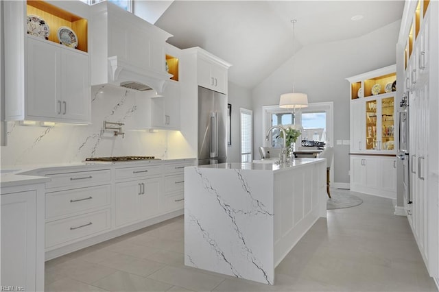 kitchen with white cabinets, a sink, gas stovetop, vaulted ceiling, and high quality fridge