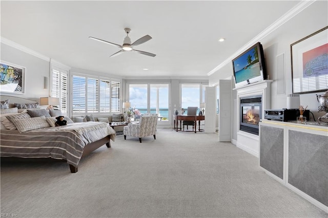 carpeted bedroom featuring crown molding, a glass covered fireplace, and multiple windows