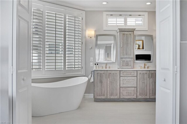 full bath featuring double vanity, a sink, a freestanding tub, and tile patterned flooring