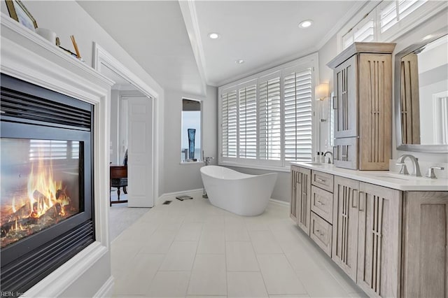 full bathroom with baseboards, a sink, double vanity, and a soaking tub