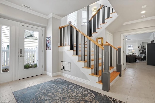 tiled entrance foyer featuring crown molding, stairway, a ceiling fan, and visible vents