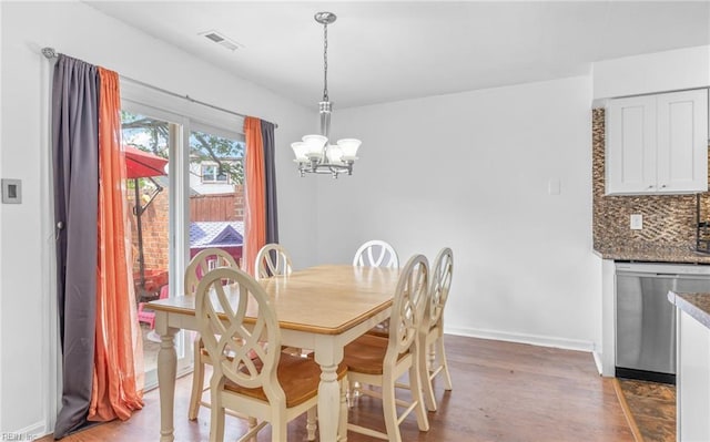 dining area featuring visible vents, baseboards, wood finished floors, and a chandelier