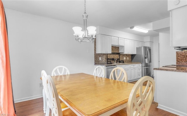 dining room with baseboards, a chandelier, and light wood-style floors