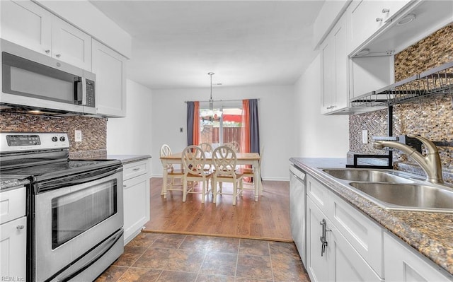 kitchen featuring white cabinets, a sink, stainless steel appliances, baseboards, and decorative backsplash