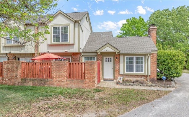 view of front of property featuring a shingled roof, a chimney, fence private yard, and brick siding