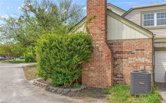 view of side of home featuring brick siding, central air condition unit, and a chimney