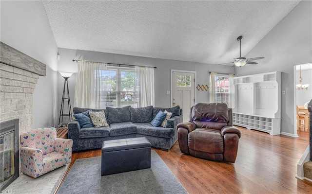 living area with a ceiling fan, a textured ceiling, vaulted ceiling, and wood finished floors