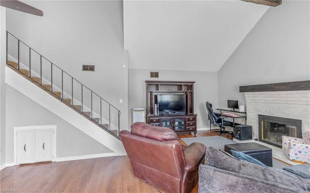 living area featuring high vaulted ceiling, stairs, wood finished floors, and visible vents