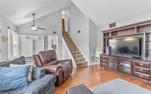living room with a ceiling fan, visible vents, stairway, and light wood-style floors