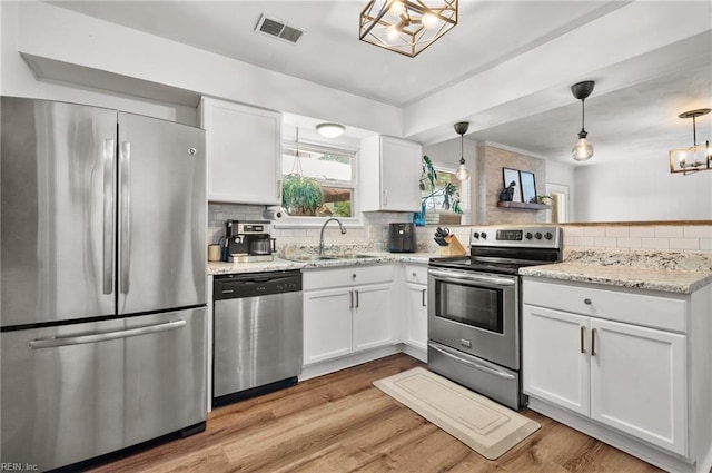 kitchen featuring visible vents, appliances with stainless steel finishes, a sink, a peninsula, and a notable chandelier
