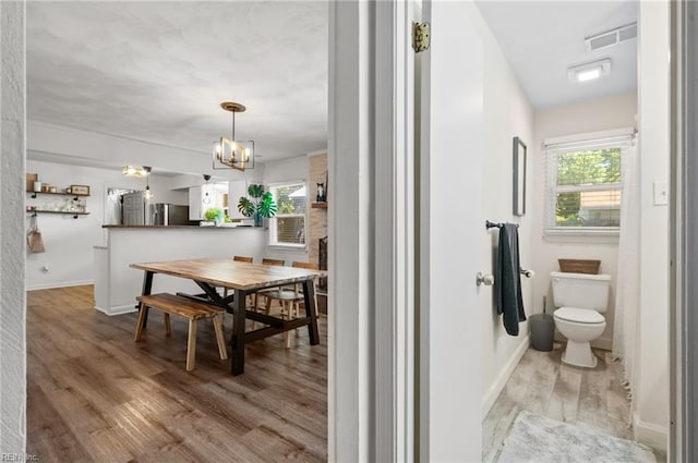 bathroom with toilet, a chandelier, baseboards, wood finished floors, and visible vents