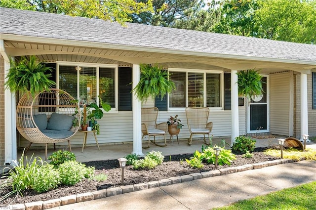 doorway to property featuring covered porch and a shingled roof